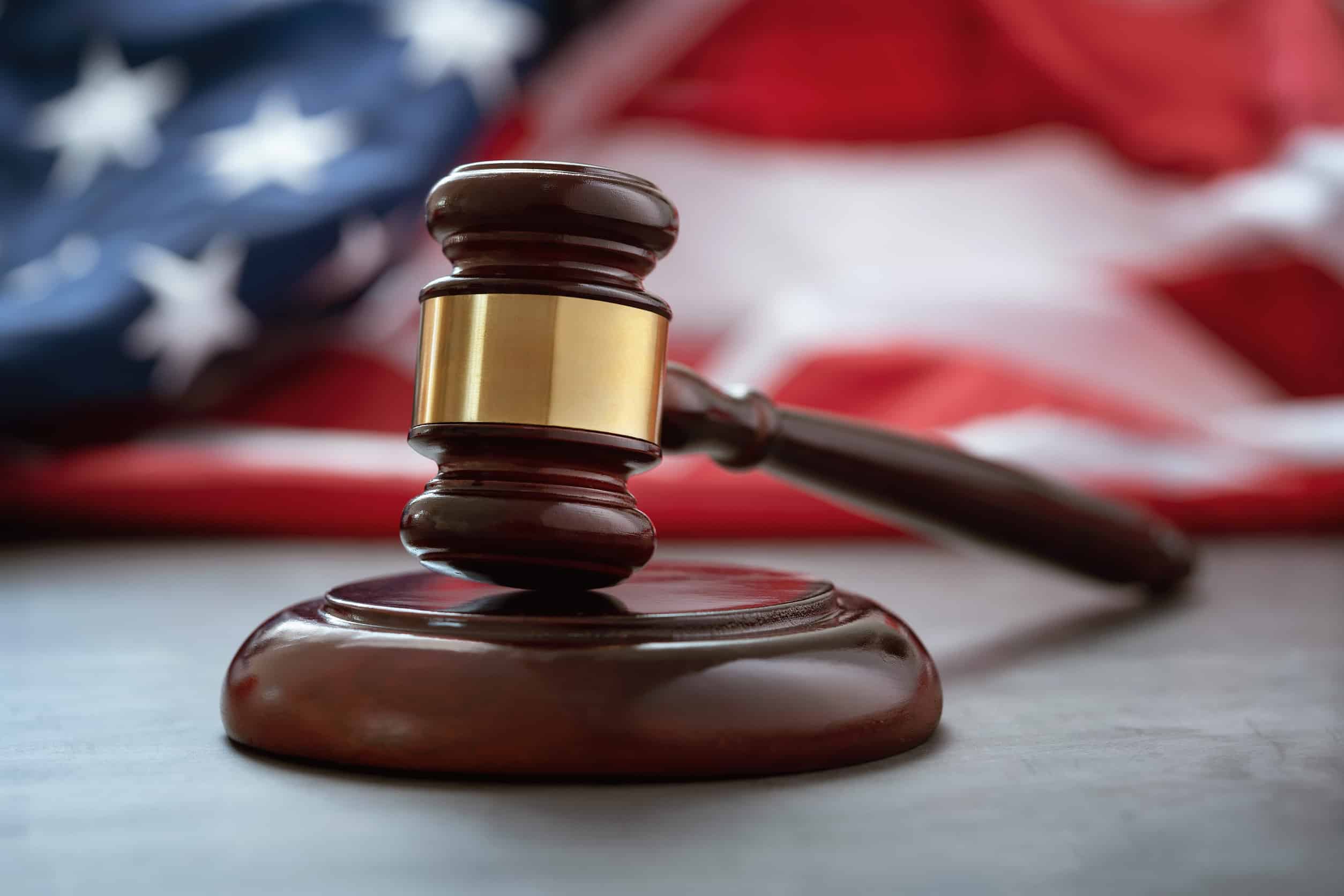 Judge's gavel resting on a sound block with an American flag in the background, representing the legal process, liability, and state and federal laws that apply to Texas truck accident claims.